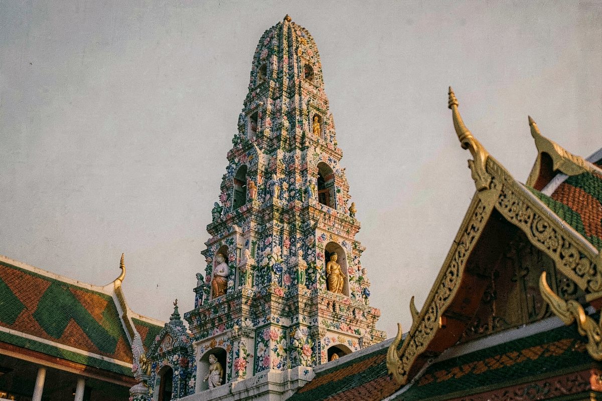 Porcelain-mosaic temple spire and tiled Thai roofs in Bangkok (illustrative image)